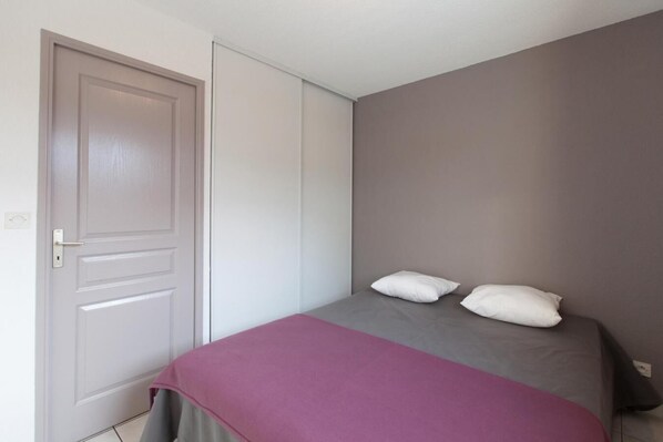 Een slaapkamer met een bed, twee kussens, een deur en een muur.