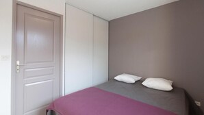 A bedroom with a bed, two pillows, a door, and a wall. - Chalet, terrace, parking, tv, 61m², Serre Chevalier (La Salle-les-Alpes)