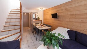 A compact living space with a staircase, a dining area, and a TV mounted on the wall. - Chalet, terrace, parking, tv, 61m², Serre Chevalier (La Salle-les-Alpes)
