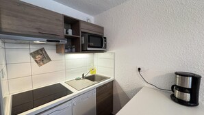 Uma cozinha compacta com micro-ondas, lava-louças e máquina de café.