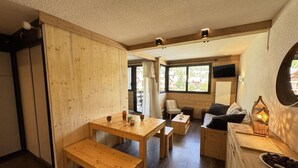 En ombonad träinredning med en matplats, en soffa och ett litet bord med en lykta.