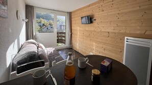 Une pièce avec un lit, une table sur laquelle se trouvent une bouteille, une tasse et une boîte.