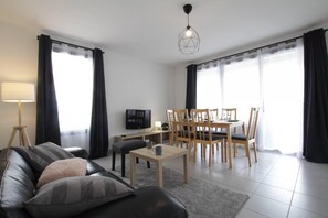 A modern living room with a sofa, coffee table, TV, and dining area with chairs and a table. - 150m from resort center, 1st floor, terrace, balcony, parking, tv, 78m², Serre Chevalier (Briançon)