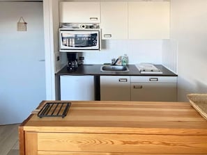 A compact kitchen with a microwave, sink, and dishwasher.