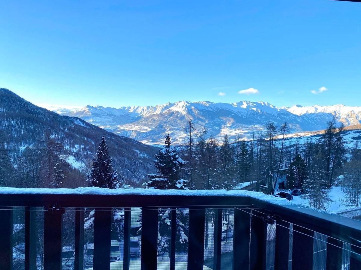 Un balcó amb vista a muntanyes i arbres coberts de neu.