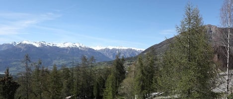 A mountain road with a view of snow-capped peaks in the distance.