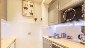 A modern kitchen with white tiles, a microwave, a dishwasher, and a sink.