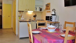 A compact kitchen with a microwave, kettle, and basic appliances. There is a dining table set with plates and glasses. - 50m from ski slopes, Ground floor, balcony, tv, ski locker, 28m², Risoul (Risoul)