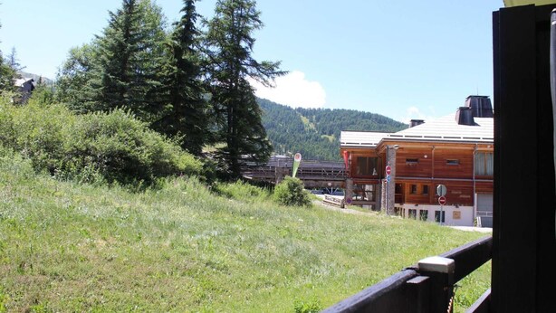 A wooden building with a balcony, surrounded by greenery and mountains in the background. - 50m from ski slopes, Ground floor, balcony, tv, ski locker, 28m², Risoul (Risoul)