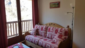 Relax in comfort near a window with a mountain view, featuring a sofa and a small table.