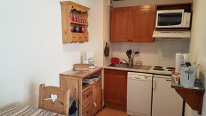 A compact kitchen with wooden cabinets, a microwave, a coffee maker, and a dishwasher. - 50m from ski slopes, 3rd floor, swimming pool, 37m², Valloire (Valloire)