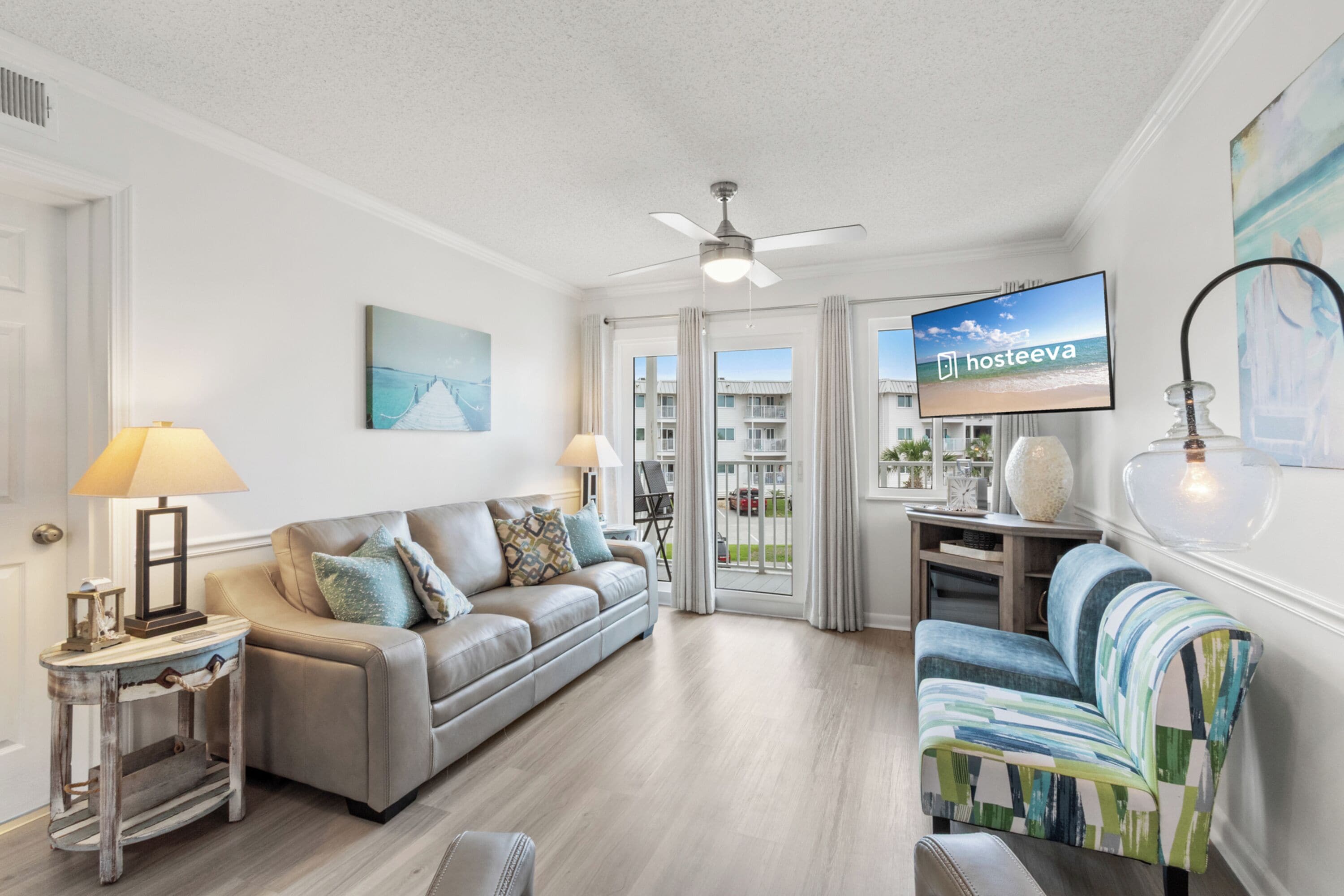 A living room with a sofa, armchairs, a TV, and a ceiling fan.