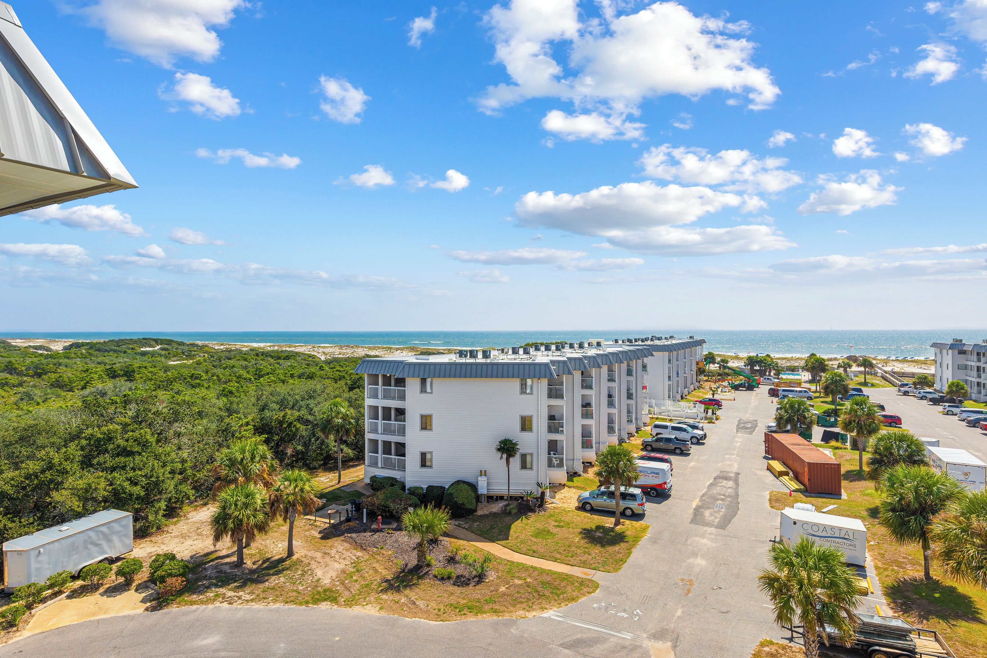 Ein Hotel an der Küste mit mehreren Etagen, einem Parkplatz und Blick auf den Strand.
