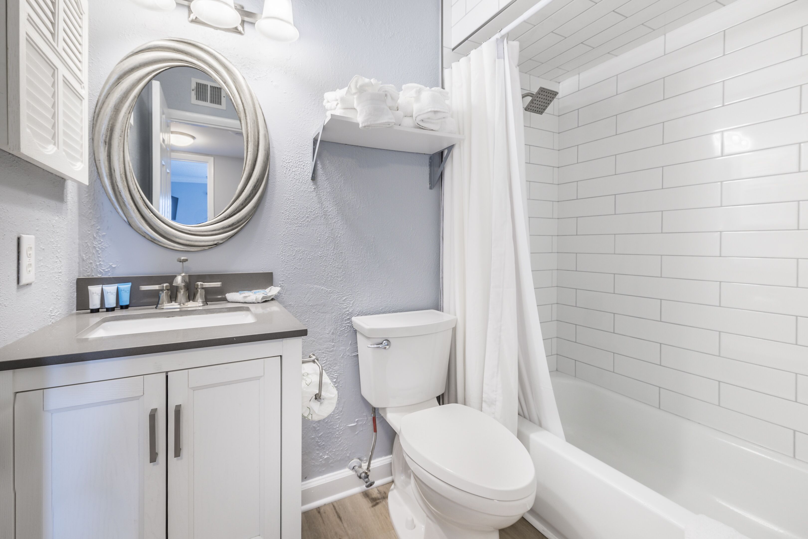 A bathroom with a white toilet, sink, and bathtub. There is a shower curtain and a mirror above the sink.