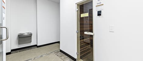 Ein Flur mit dem Eingang zu einer Sauna, einer Handstange, einem Handtuchspender und einem gemusterten Boden.