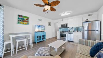 A modern kitchen with white cabinets, a stainless steel refrigerator, and a microwave.