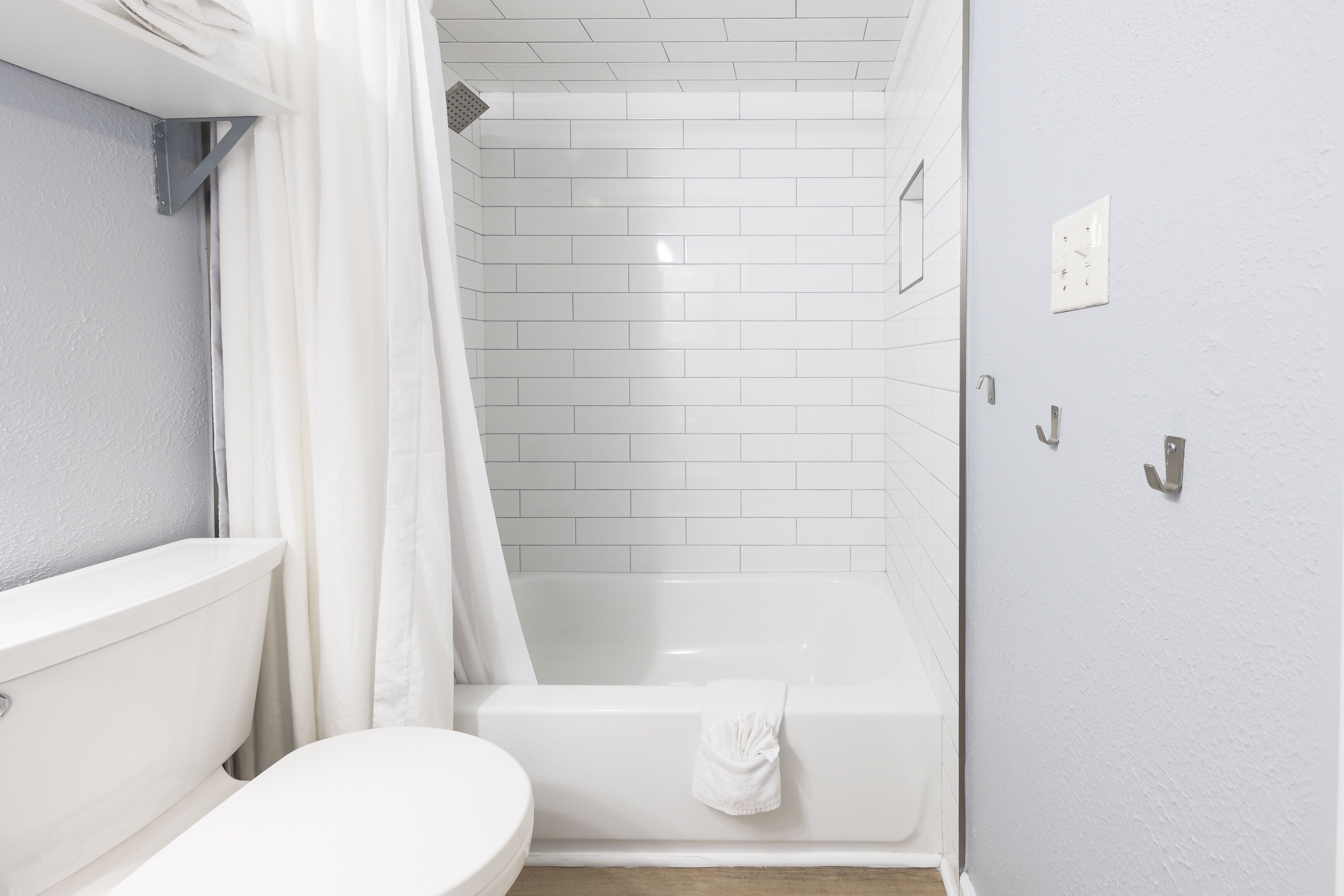 Un baño con inodoro blanco, bañera y cortina de ducha.