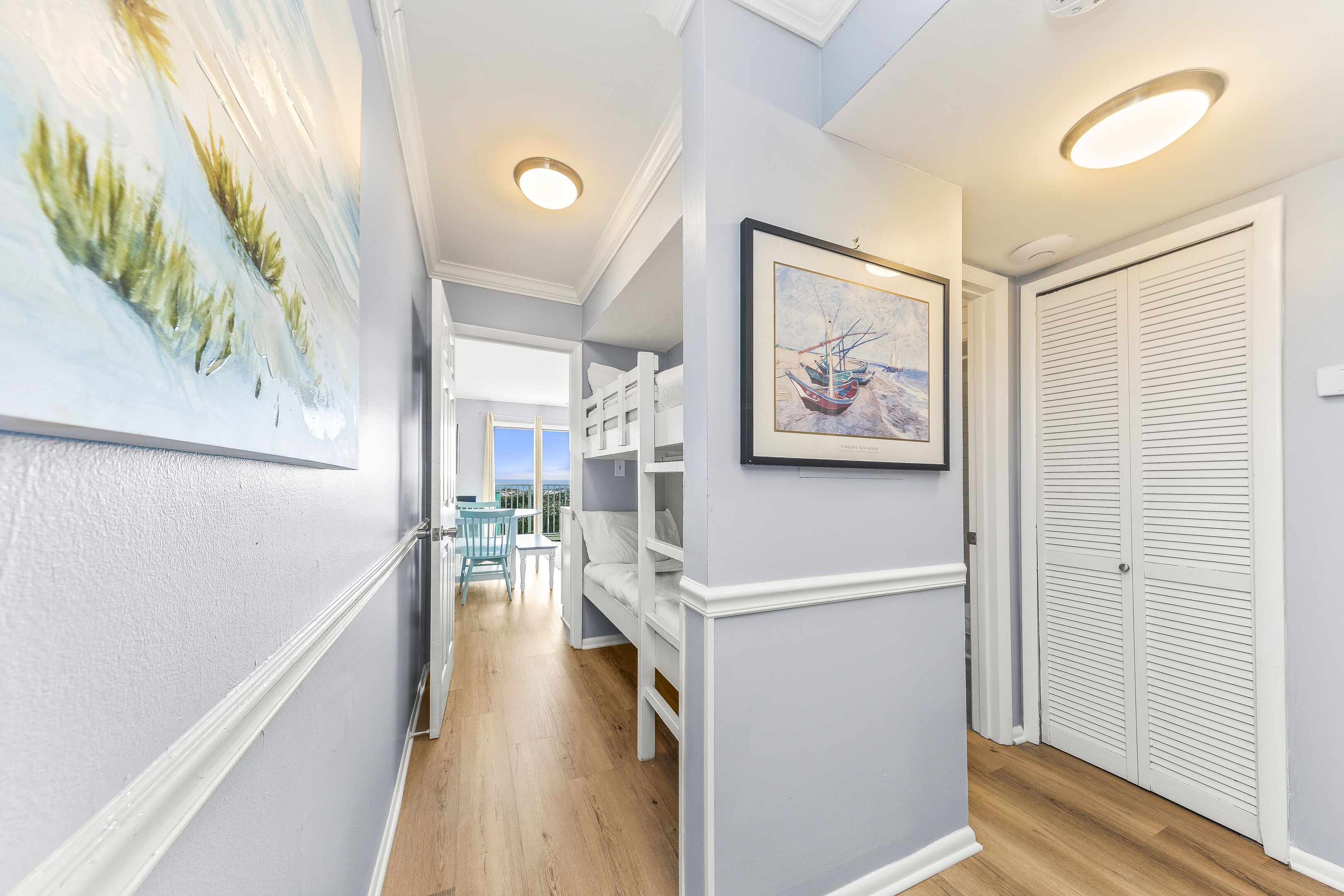 A hallway with a bunk bed, a framed picture, and a white door.