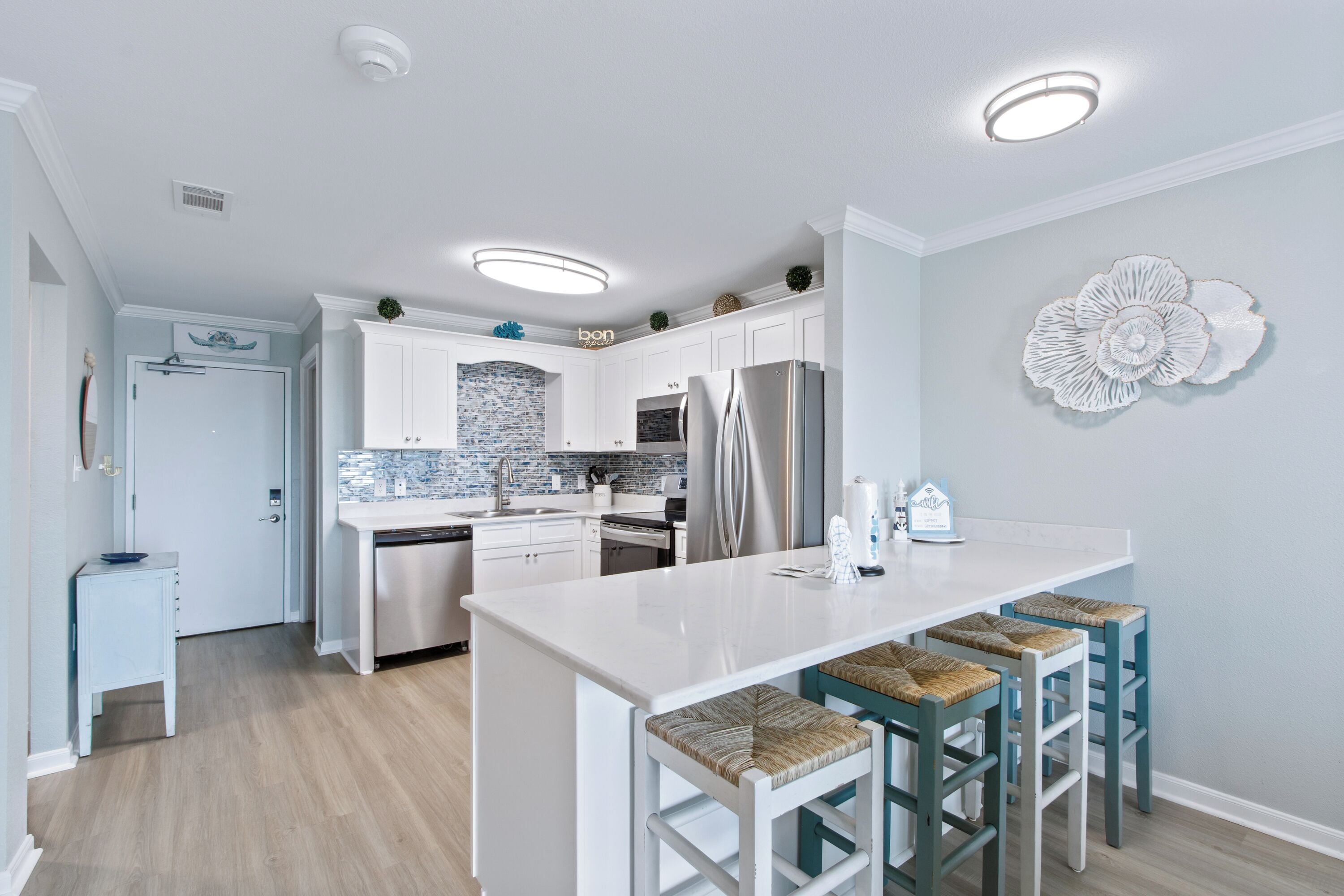 A modern kitchen with white cabinets, a stainless steel refrigerator, and a central island with bar stools.