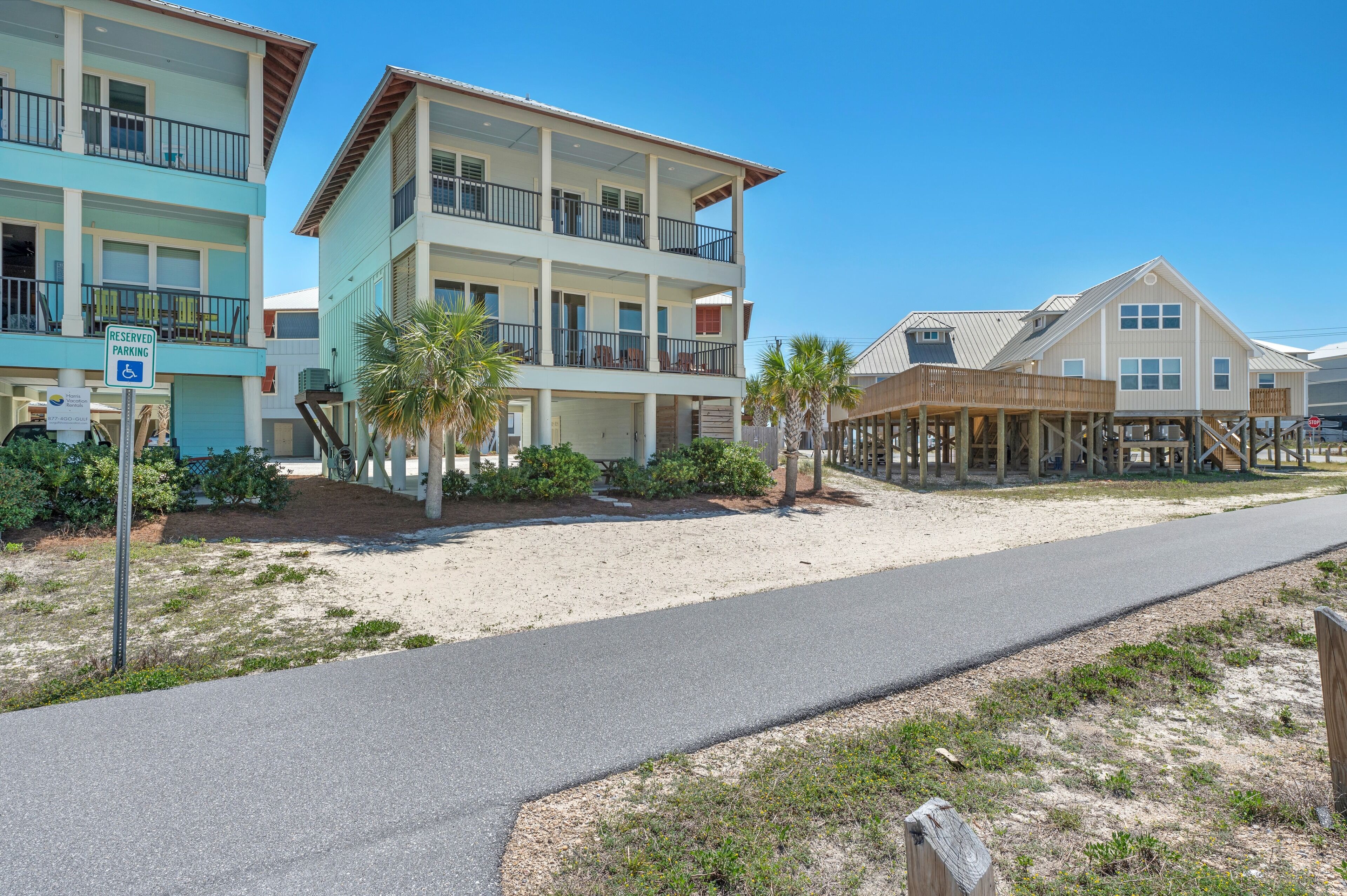 Un hôtel situé en bord de mer, doté de nombreux balcons, d’une plage de sable et d’une jetée en bois.
