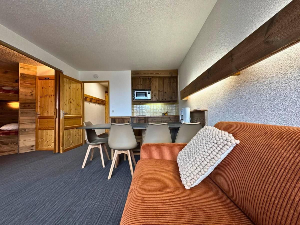 A compact living space with a sofa, chairs, a dining table, and a kitchenette.