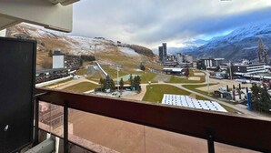 A view from a balcony overlooking a ski resort with buildings, a ski lift, and a mountainous landscape. - 10m from ski slopes, 7th floor, balcony, tv, 28m², Les Menuires (Les Menuires)