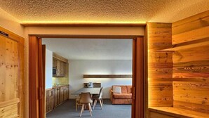 A wooden interior with a dining area, a sofa, and a kitchen visible through an open doorway. - 10m from ski slopes, 7th floor, balcony, tv, 28m², Les Menuires (Les Menuires)
