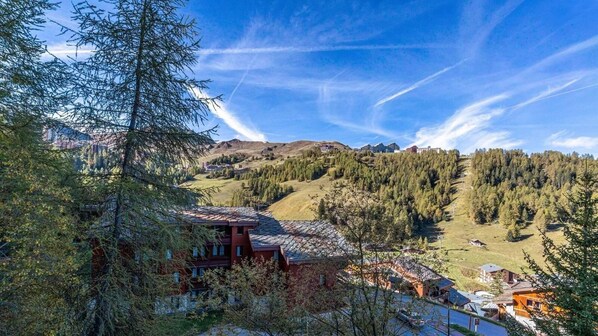 A mountain lodge with a red building, surrounded by dense forests and a clear sky.