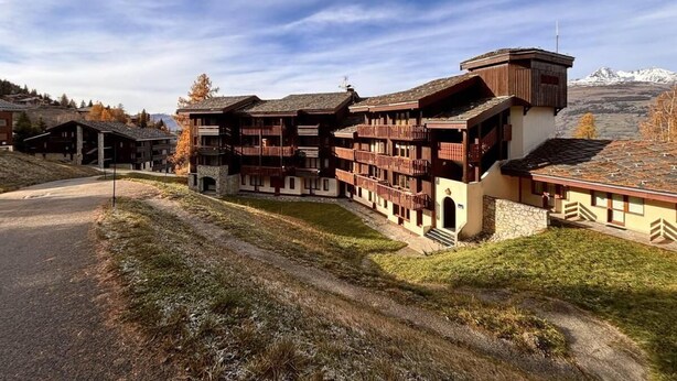 A multi-story hotel with balconies, a stone facade, and a view of snow-capped mountains. - 100m from ski slopes, 3rd floor, view mountain, balcony, tv, ski locker, 33m², Montchavin La Plagne (Bellentre)