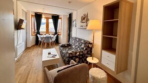 A compact living space with a sofa, dining table, chairs, a lamp, and a TV. - 100m from ski slopes, 3rd floor, view mountain, balcony, tv, ski locker, 33m², Montchavin La Plagne (Bellentre)
