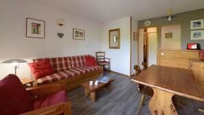 Ein gemütliches Wohnzimmer mit einer Couch, Sesseln, einem Holztisch und einem Essbereich.