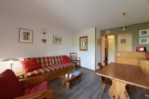 A cozy living room with a sofa, chairs, a wooden table, and a dining area. - 100m from ski slopes, 4th floor, view ski slopes, balcony, tv, ski locker, 32m², La Plagne (La Plagne)