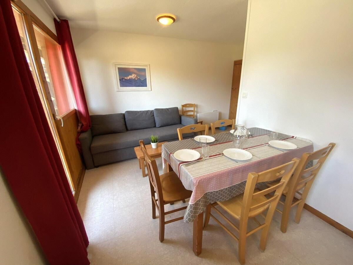Un coin repas avec une table dressée pour quatre personnes, un canapé en arrière-plan et une fenêtre avec des rideaux.