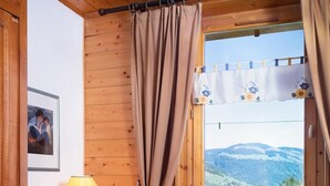 Ein gemütliches Zimmer mit einem Holztisch, einem Stuhl und einem Fenster mit Vorhängen.