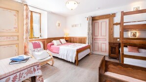 Ein gemütliches Schlafzimmer mit einem hölzernen Bett, einem Sessel, einem kleinen Tisch mit einem Buch und einem Schlafstapel.