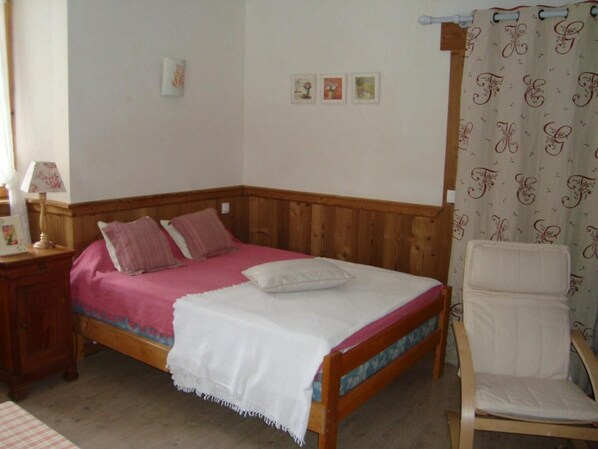 A bedroom with a wooden bed, a chair, and a nightstand.