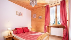 A wooden-paneled room with a bed, two bedside lamps, and a window with red curtains. - 300m from ski slopes, parking, tv, 44m², Arêches-Beaufort (Beaufort)