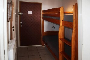 A narrow room with a door, a radiator, and two bunk beds.