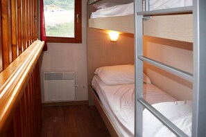 A bunk bed room with a window, a heater, and a red curtain.