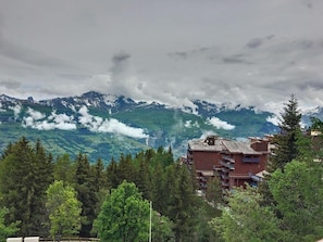Eine gebirgige Landschaft mit einem Gebäude, das mehrere Balkone und ein rotes Dach hat.