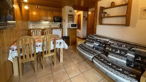 A cozy kitchen with wooden cabinets, a dining table with chairs, and a sofa with patterned cushions. - 50m from ski slopes, 1st floor, view mountain, balcony, tv, ski locker, 29m², Les Saisies (Les Saisies)