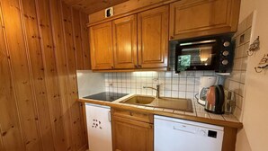 A compact kitchen with wooden cabinets, a built-in microwave, a sink, and a dishwasher. - 50m from ski slopes, 1st floor, view mountain, balcony, tv, ski locker, 29m², Les Saisies (Les Saisies)