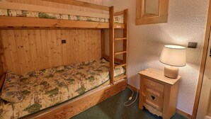 A bunk bed room with a wooden ladder, a bedside table with a lamp, and a mirror on the wall. - 10m from ski slopes, 4th floor, 27m², Méribel-Mottaret (Méribel - Les Allues)