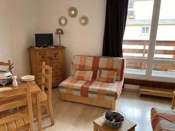 A cozy living room with a wooden sofa, a dining table with chairs, a small wooden cabinet, and a television on a stand. - 200m from resort center, 4th floor, tv, 25m², Orcières Merlette 1850 (Orcières)