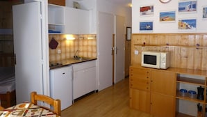 Cocina compacta con armarios blancos, un microondas y una repisa de madera.