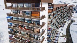 Ett hotell med flera våningar och balkonger, en skidbacke i bakgrunden och ett bergigt landskap.
