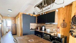 Eine kompakte Küche mit Holzausstattung, einer zentralen Kücheninsel und einem Essbereich mit Holztisch.