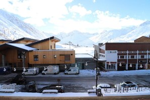Un edificio moderno con fachada de madera y exterior blanco, rodeado de montañas nevadas.
