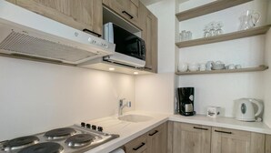 A modern kitchen with a stove, microwave, and white cabinets. - 100m from resort center, 4th floor, balcony, tv, ski locker, 30m², Tignes (Tignes)