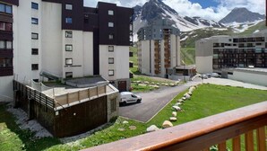 Et moderne bykompleks med flere etager, parkeringsplads og bjergudsigt i baggrunden.